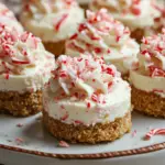 No-bake peppermint cheesecake bites with a graham cracker crust, topped with crushed candy canes, perfect for holiday parties and gatherings.