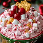 A festive bowl of Christmas Cherry Cheesecake Fluff topped with whole cherries, graham cracker crumbs, and holiday sprinkles.