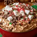 A festive bowl of Christmas Chocolate Lovers’ Fluff topped with red and green sprinkles, chocolate shavings, and mini candy canes, served in a holiday setting.