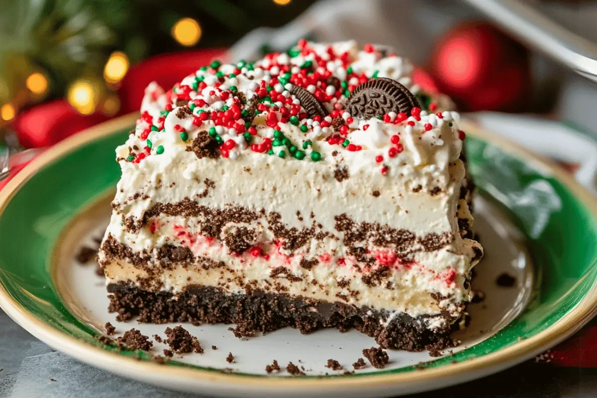 A festive slice of No-Bake Christmas Oreo Lasagna with creamy layers of cheesecake, chocolate pudding, and whipped topping, garnished with sprinkles.