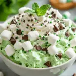Lucky Mint Shamrock Fluff served in a bowl, garnished with whipped cream, green sprinkles, and fresh mint leaves