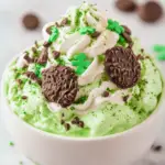 Shamrock Cheesecake Fluff served in a bowl with green sprinkles, marshmallows, and mint leaves