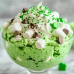 Shamrock Shake Fluff served in a clear bowl, topped with green sprinkles and marshmallows