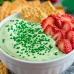 Shamrock Sugar Cookie Dip in a bowl, garnished with green sprinkles and mini shamrock candies