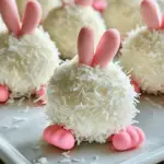 A plate of Bunny Butt Oreo Balls decorated with mini marshmallows, pink candy feet, and white chocolate