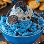 A vibrant blue bowl of Cookie Monster Fluff topped with cookies and whipped cream