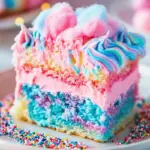 A slice of Cotton Candy Poke Cake with pastel swirls, whipped topping, and sprinkles