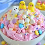 A bowl of pastel-colored Easter Marshmallow Fluff topped with mini marshmallows and chocolate eggs