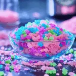 Colourful homemade Pop Rocks candy in pink and blue, broken into shards on parchment paper.