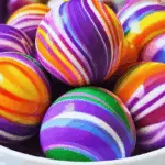 DIY Homemade Rainbow Bouncy Balls made with glue, borax, and food colouring, arranged on a colourful surface.